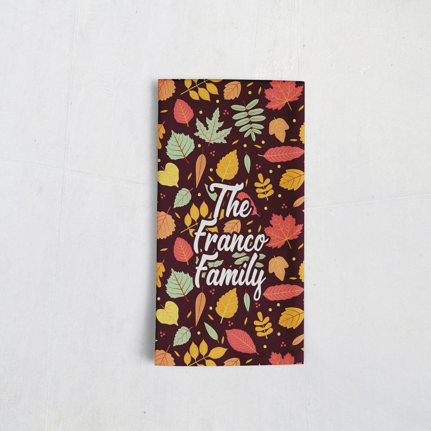 A tea towel adorned with vibrant autumn leaves and delicate patterns, crafted by Sam and Zoey for a touch of seasonal charm in kitchen decor