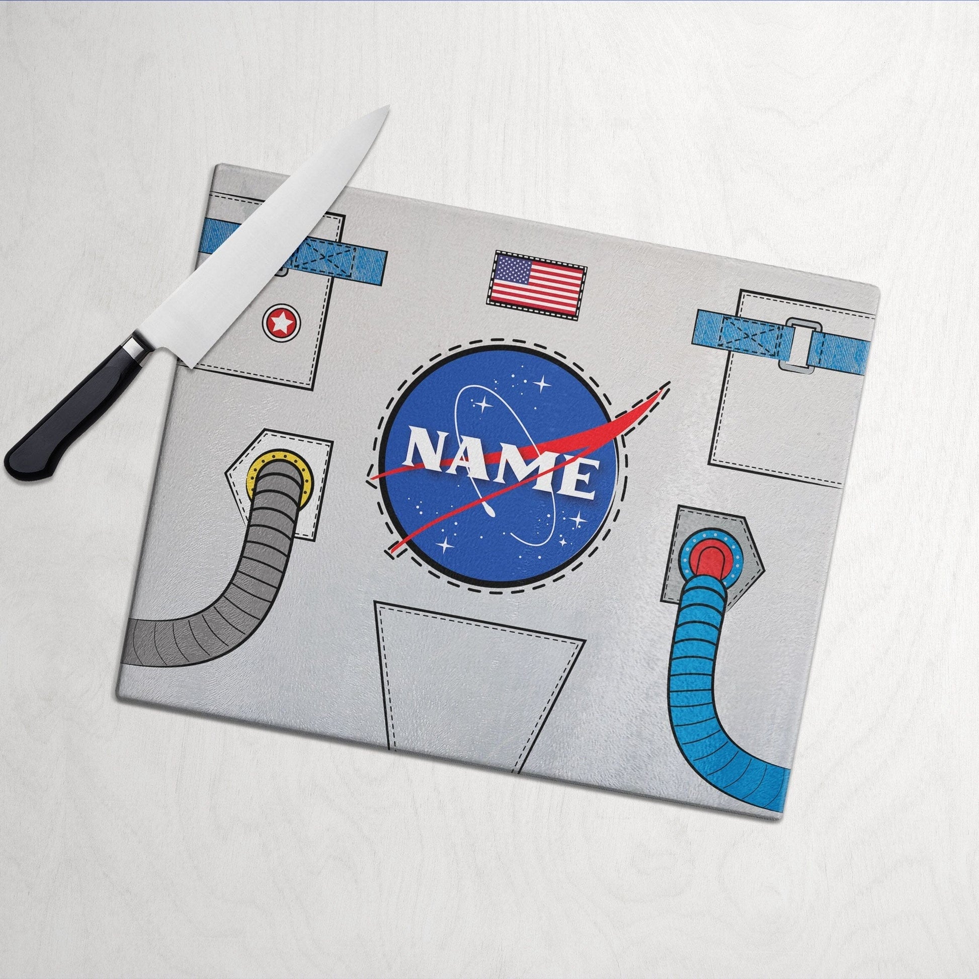 A glass cutting board with a lost in space design on a white wooden surface and knife on side