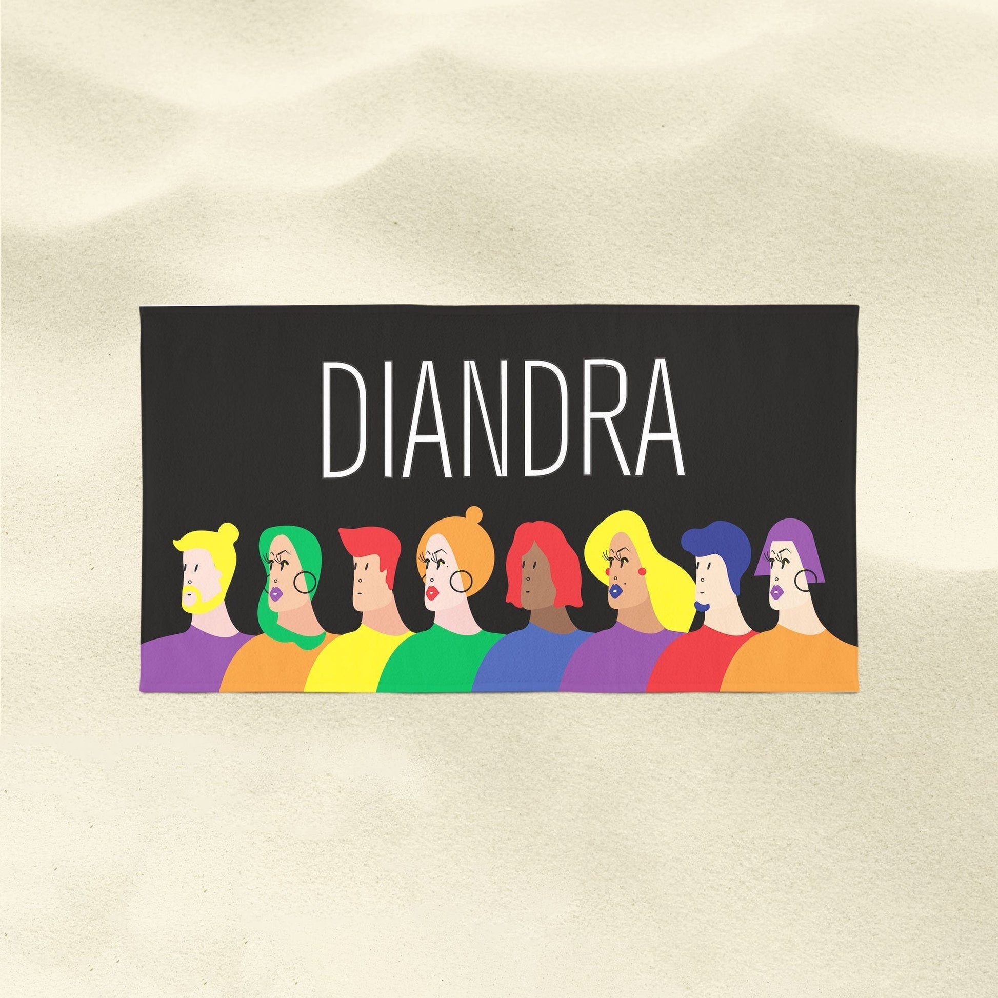 A faces of LGBTQ Pride beach towel with customized name 'Diandra' on a sandy surface