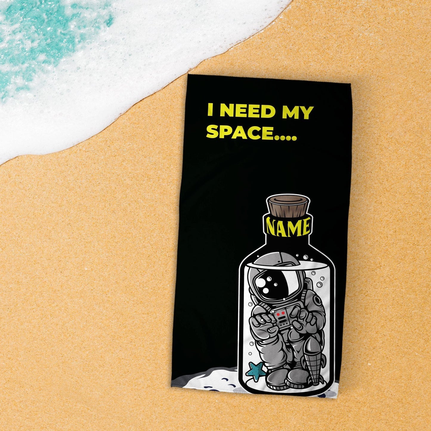 A 'I need my space' beach towel lying flat on beach, and an incoming wave