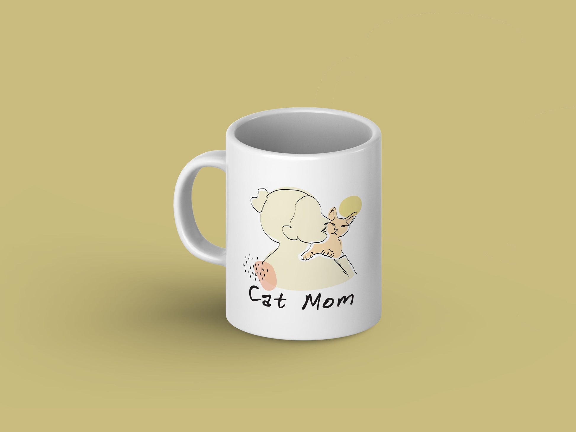 White ceramic mug with "Cat Mom" in bold black letters, decorated with cute cat face illustrations and paw prints.