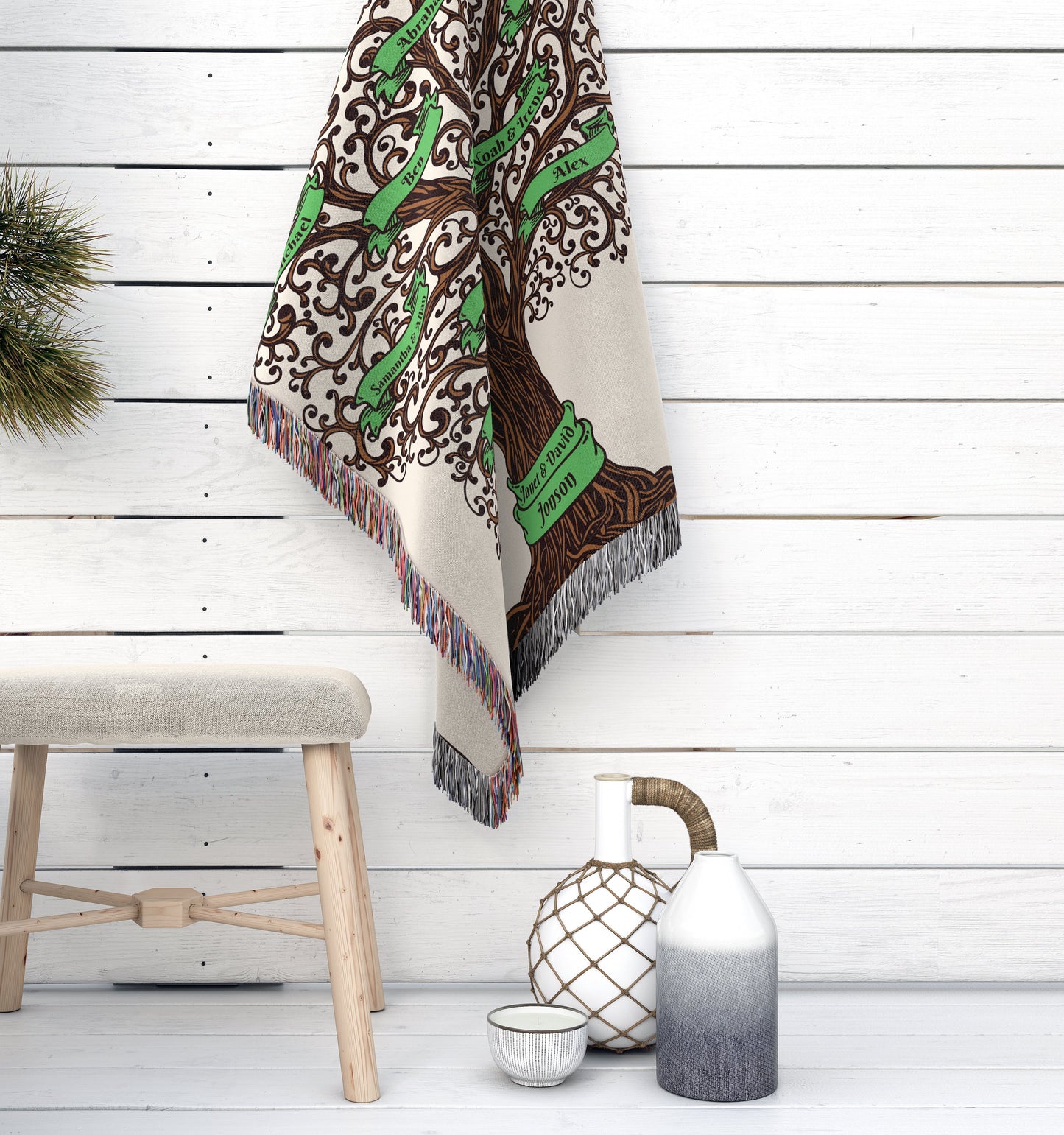 Woven throw blanket with a family tree design and green banners hanging against a white shiplap wall, beside decor items.