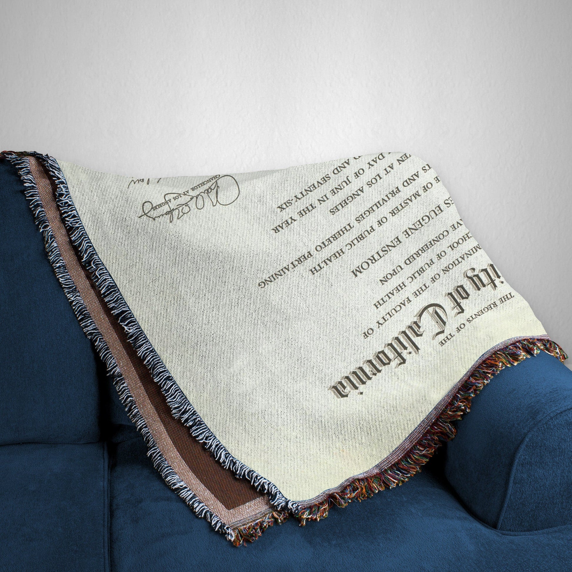 Cozy throw blanket with a printed diploma certificate design with detailed text, draped over a blue couch.