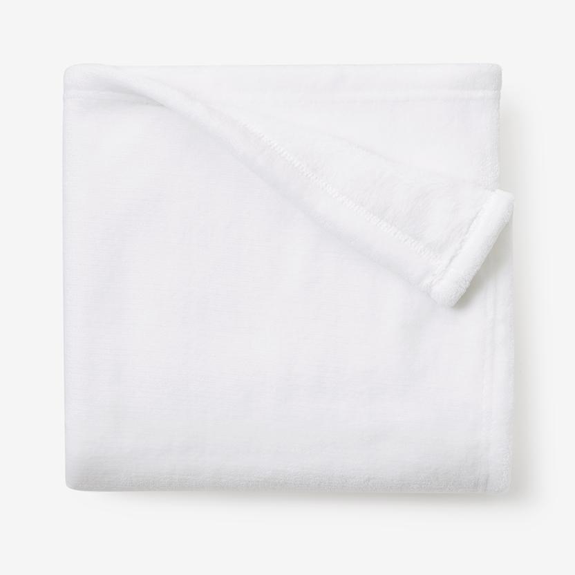 Folded white fleece blanket on a white surface