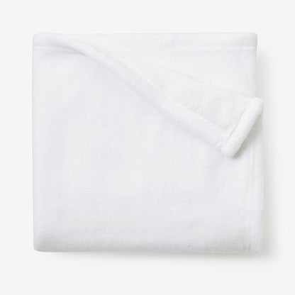 Folded white fleece blanket on a white surface