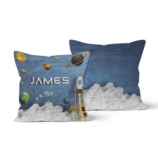 Spaceship-themed throw pillow personalized with the name "James," featuring planets, stars, and a rocket launching amidst clouds.