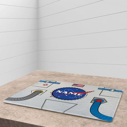 A glass cutting board with astronaut suit design on a white wooden surface and knife on side