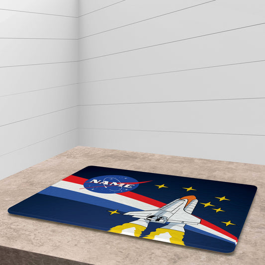 A glass cutting board with a nasa launch design, cherry tomatoe, veggies and knife on side, on a grey surface