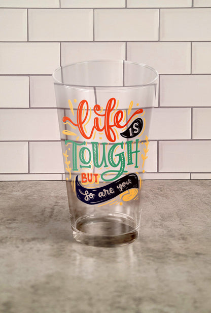 Life Is Tough But So Are You transparent Tumbler Glass against a slipslap wall