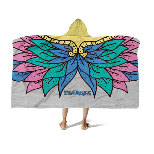 A person wearing a multi-color hooded blanket with Floral wings design and the name "Theresa" at the center-bottom on a white background.