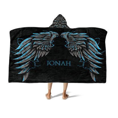 A person wearing a black hooded blanket with griffin wings designs in grey and sky-blue and the name "Jonah" at the center-bottom on a white background.