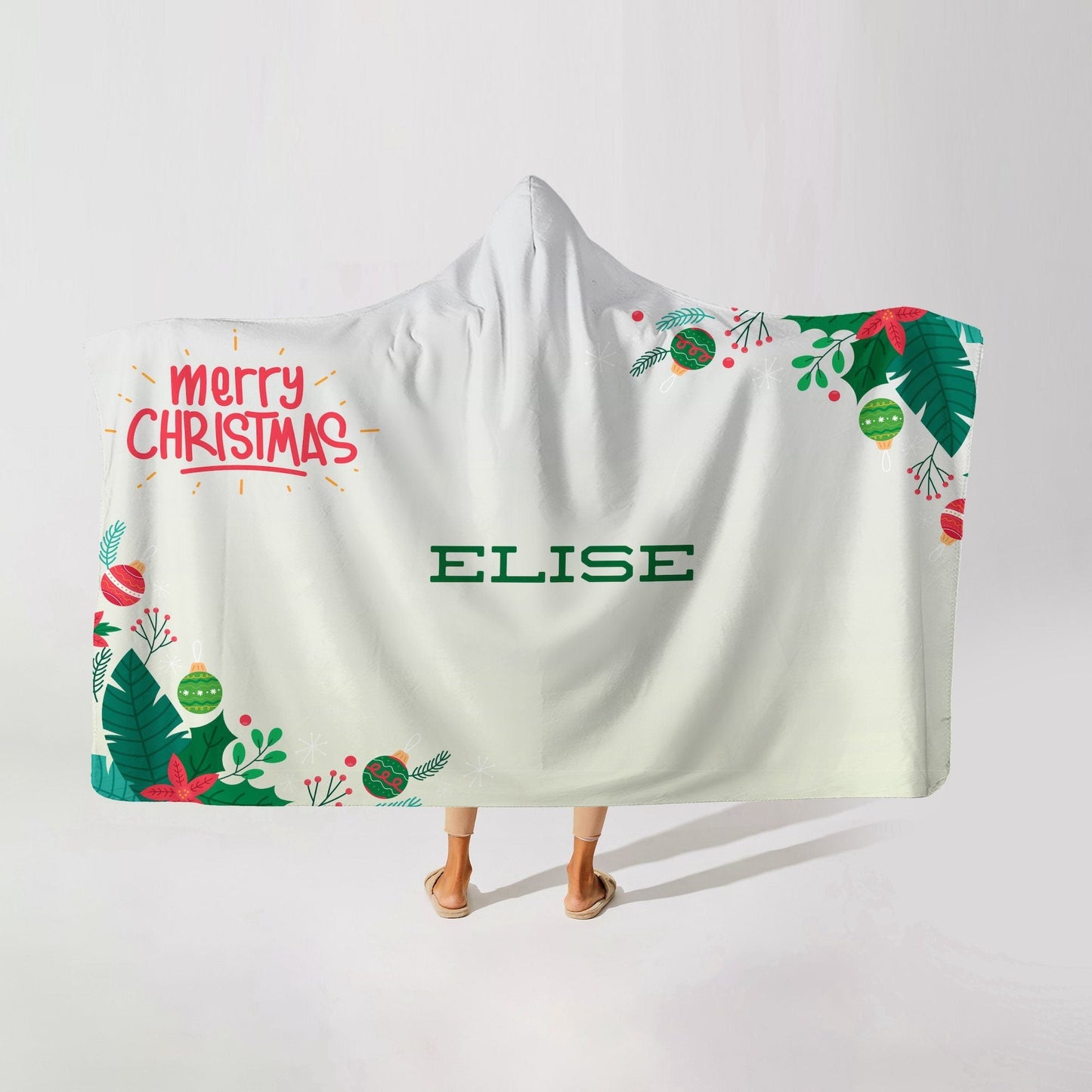 A person wearing a white hooded blanket with merry christmas written in red and the name "Elise" at the center on a white background.