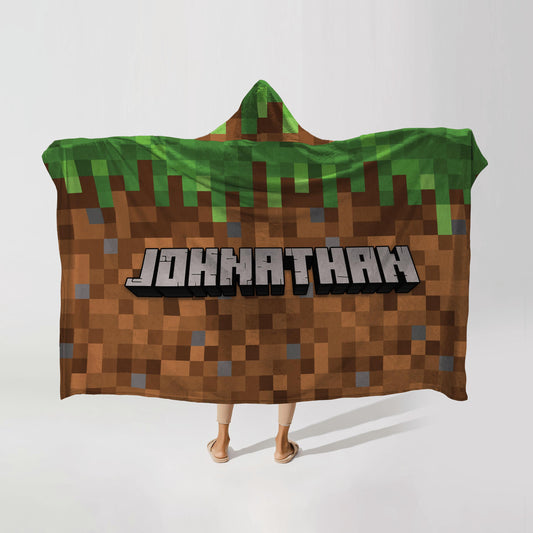 Person wearing a hooded fleece blanket with a pixelcraft design, featuring the name "Johnathan" in bold letters