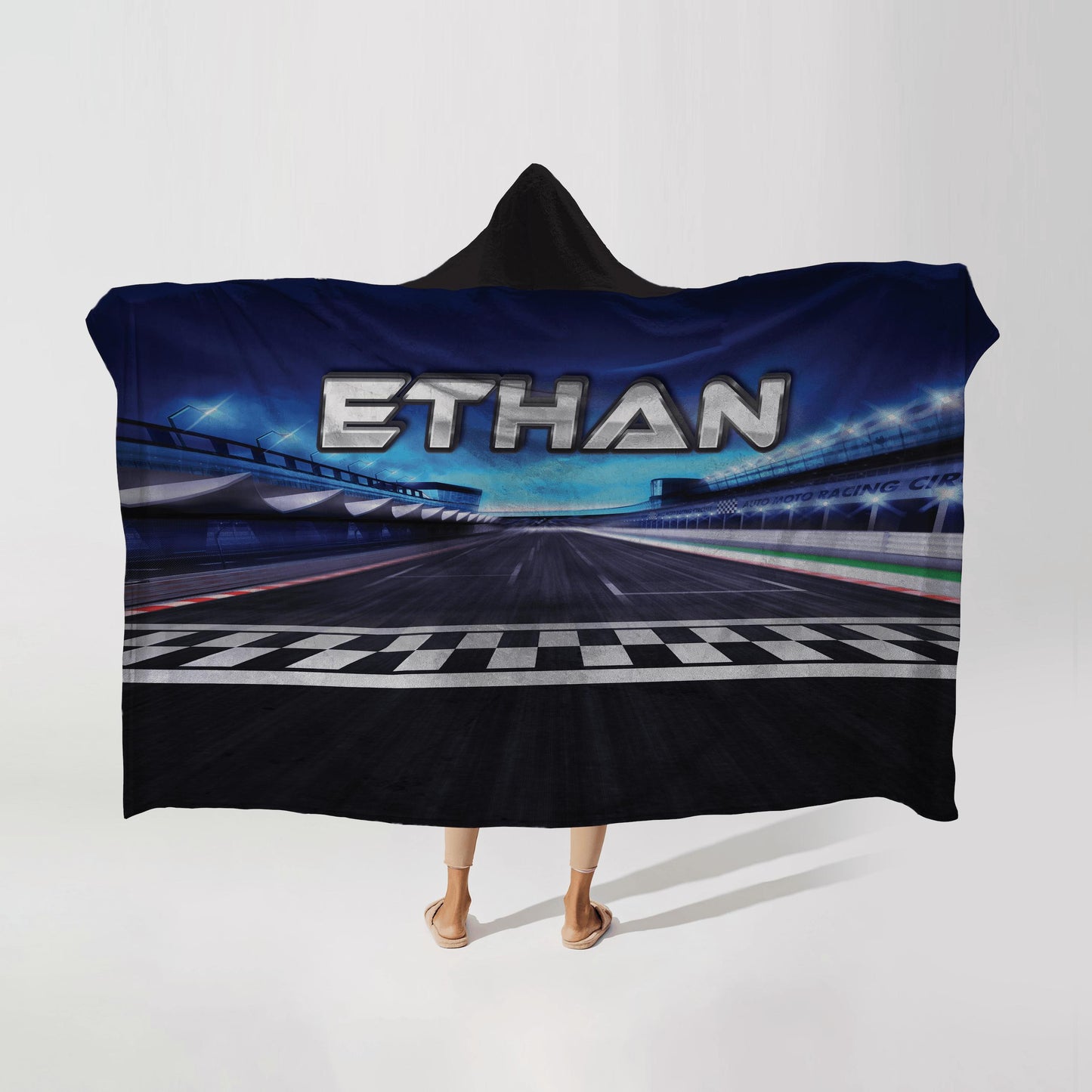 Person wearing a hooded fleece blanket with a race track design, featuring the name "Ethan" in bold letters