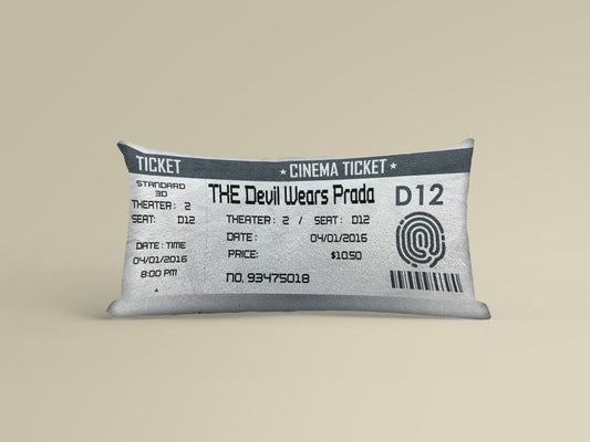 A personalized white movie ticket pillow on a yellowish background with thumb print, bar code and movie number