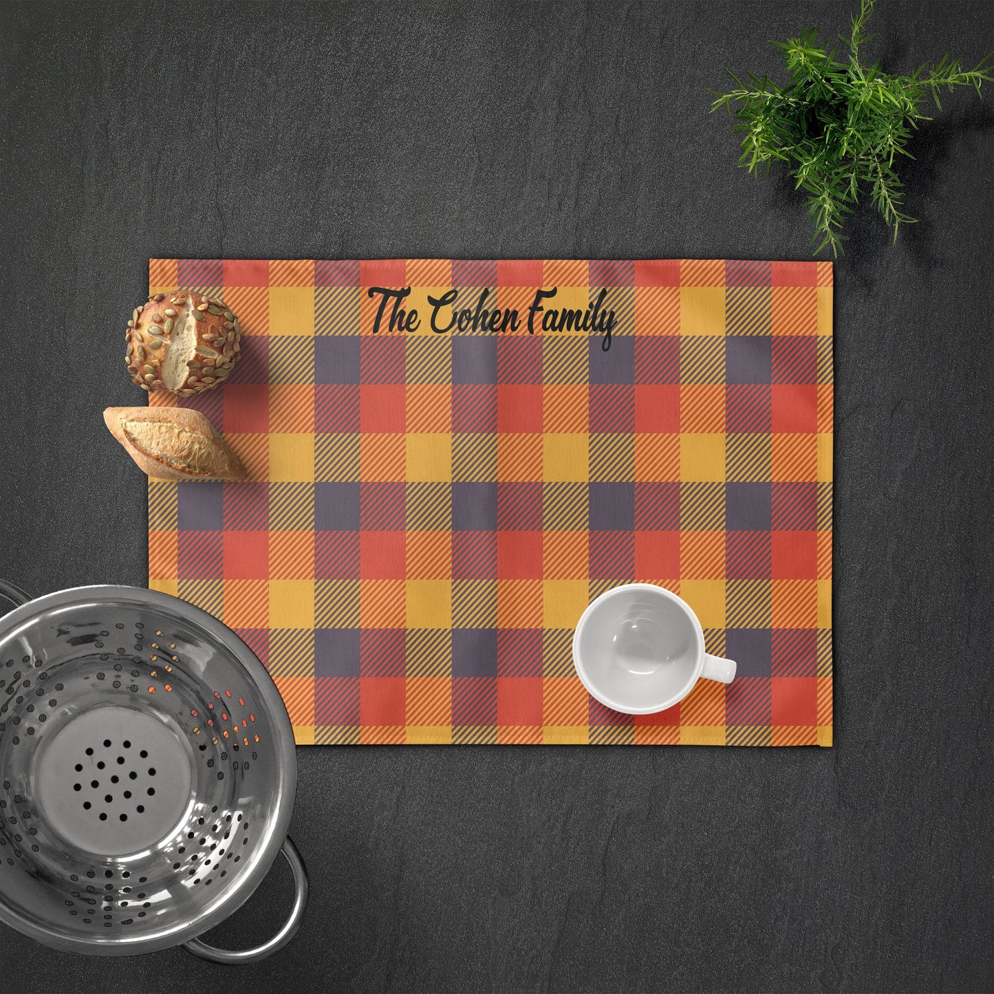 A personalized placemat with a fall plaid pattern in warm tones, featuring a name in a stylish script.