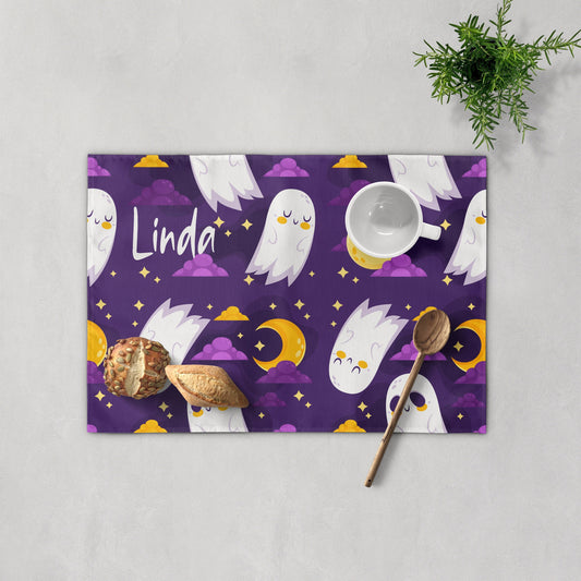 Personalized purple placemat featuring cute white ghosts, moons, and stars with the customized name "Linda" printed.