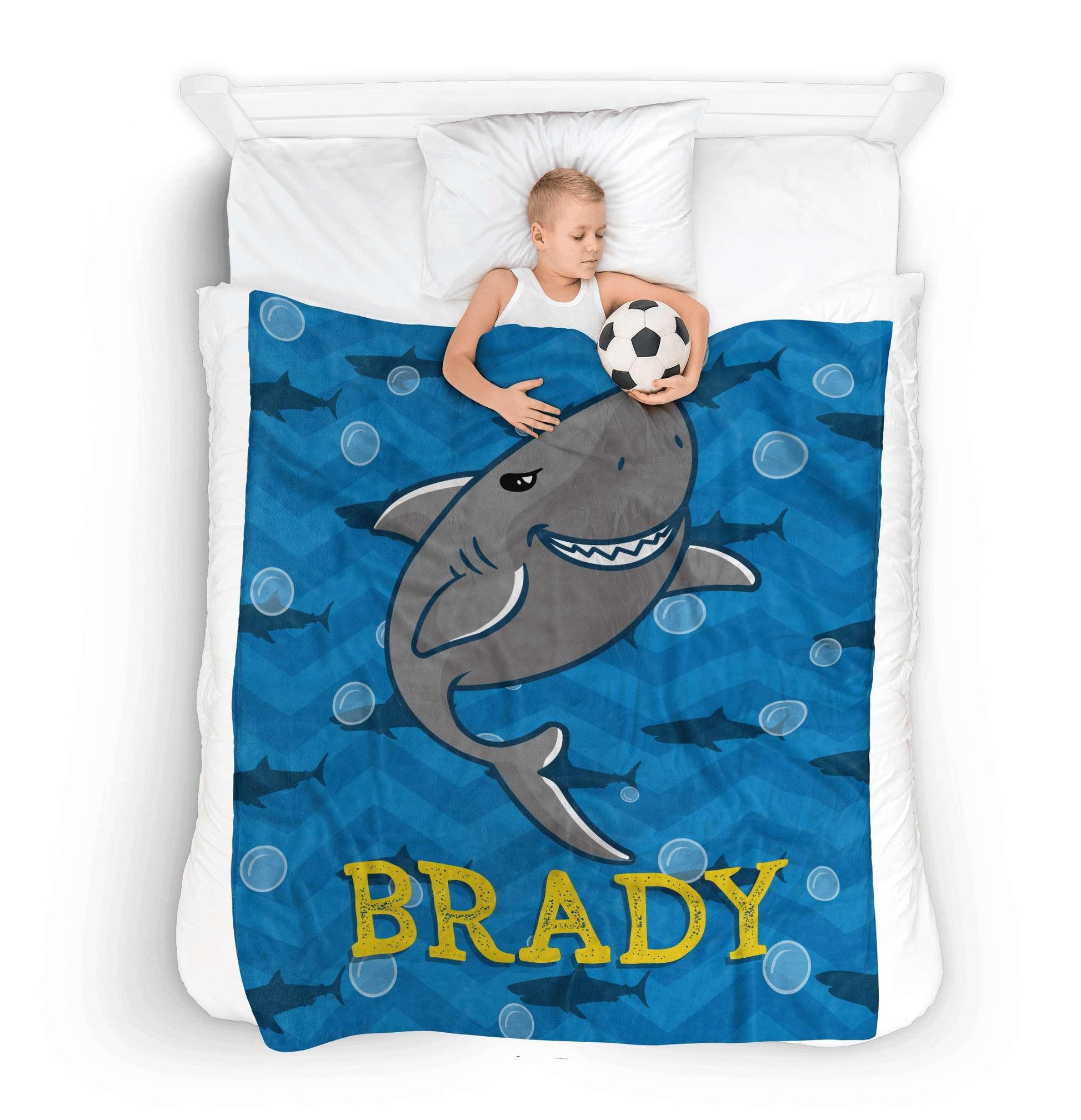 Kid sleeping in bed with a soccer ball using cute Shark custom Fleece Throw Blanket with his name Brady on it