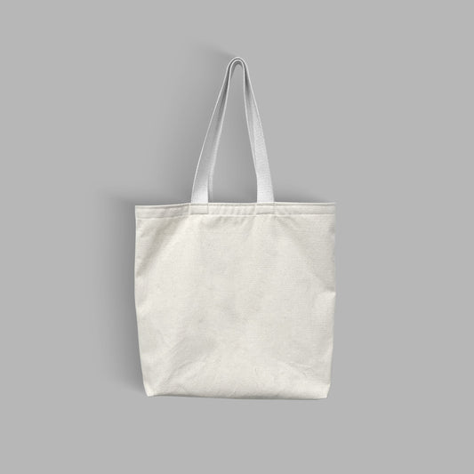 A white Canvas Tote bag with white handle displayed on a grey surface